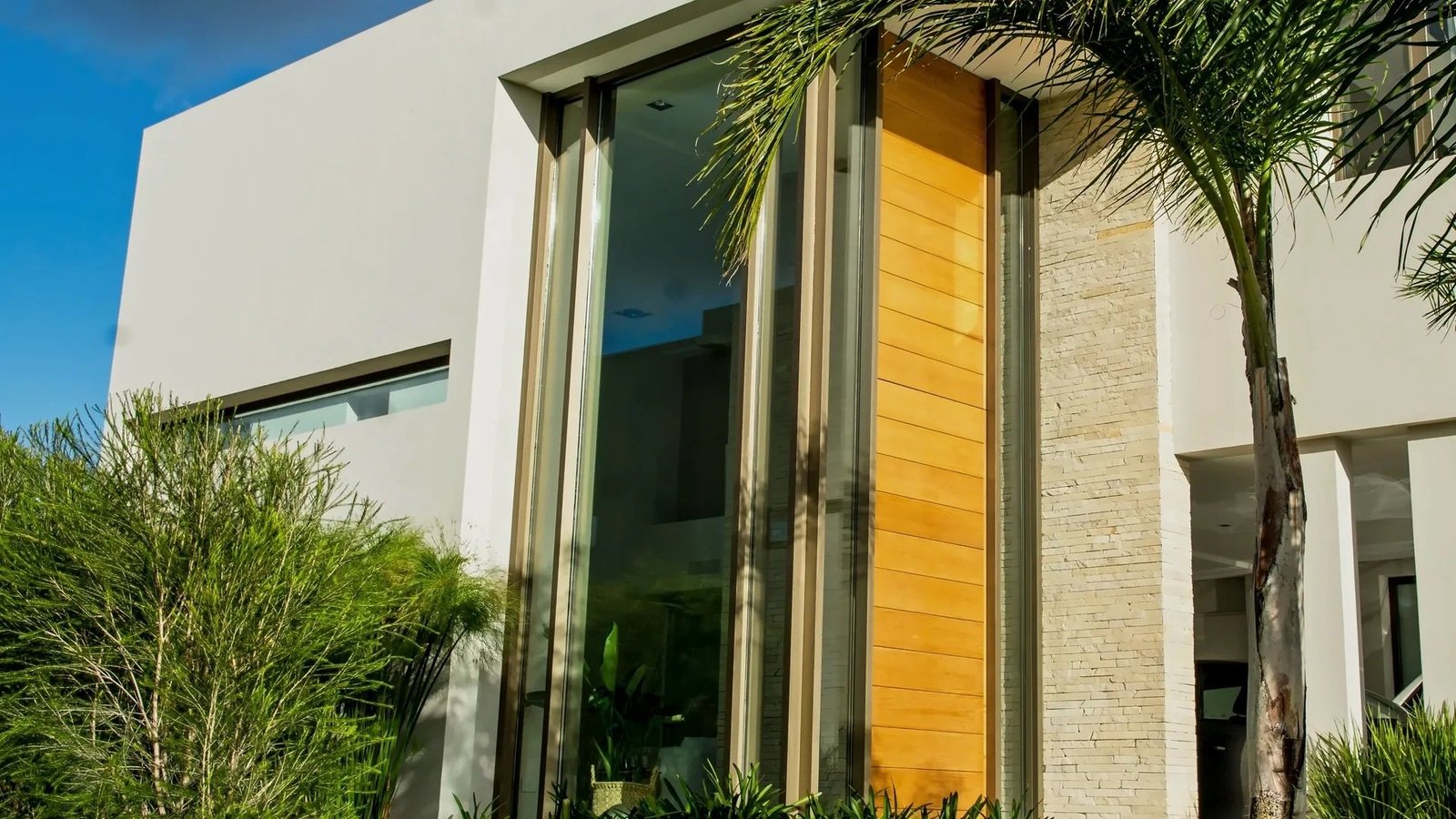 Residencia en Lomas. Paños fijos de doble altura junto a la puerta de madera.